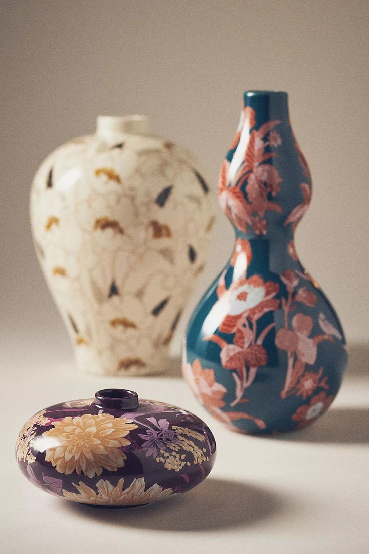 three colorful vases sitting on top of a white table next to eachother