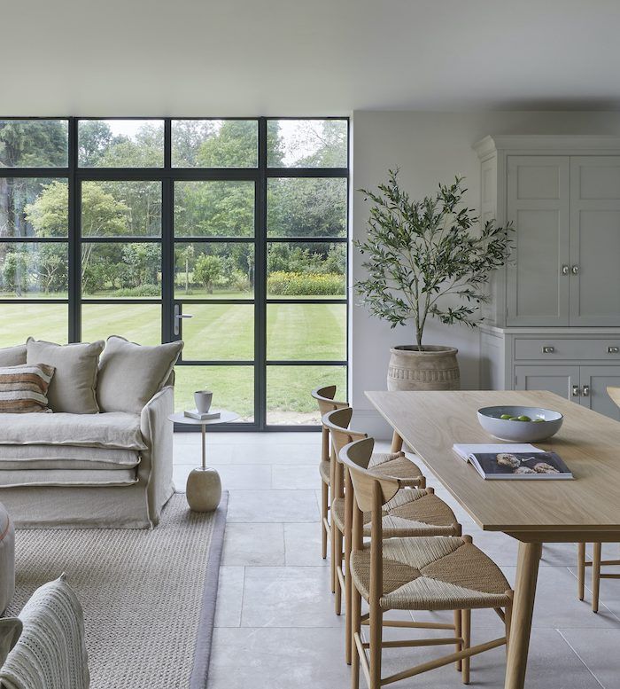 a living room filled with lots of furniture next to a large glass wall window covered in trees