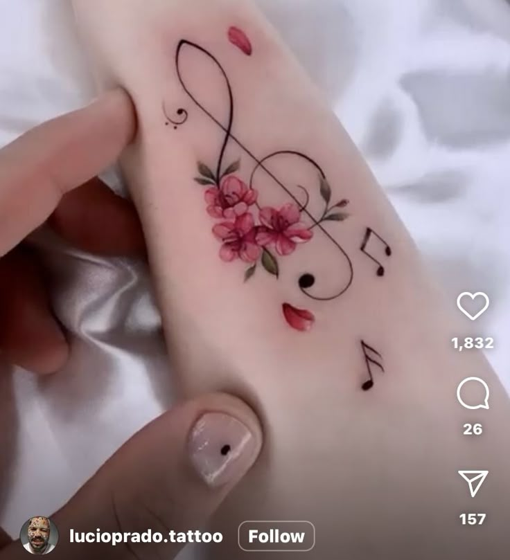 a person is holding up a tattoo with music notes and flowers on it