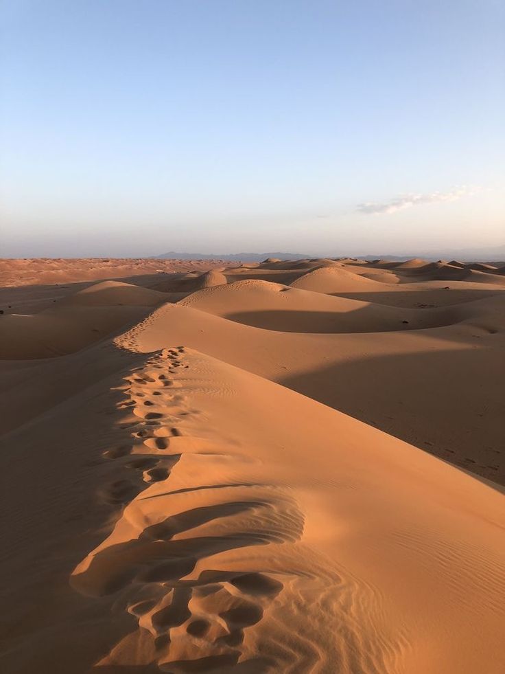 footprints in the desert sand dunes under a blue sky