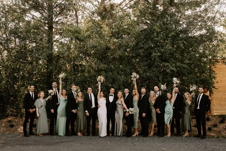 a large group of people standing next to each other in front of trees and bushes