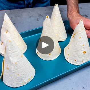 three burritos sitting on top of a blue tray next to a person's hand