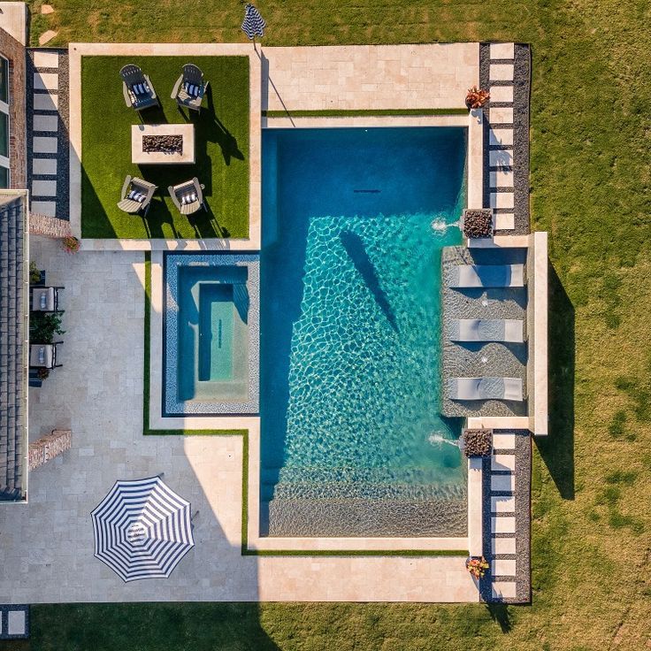 an aerial view of a pool and patio with umbrellas in the grass next to it