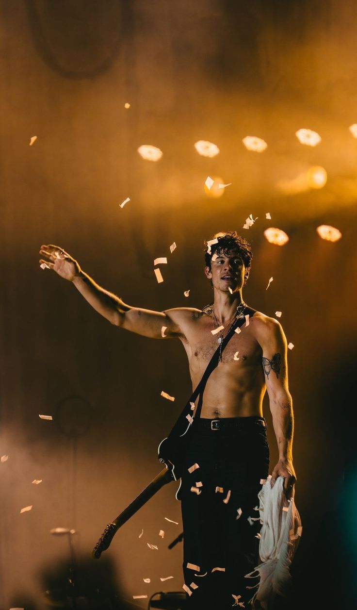 a man standing in front of a stage with confetti all around him and his arms out