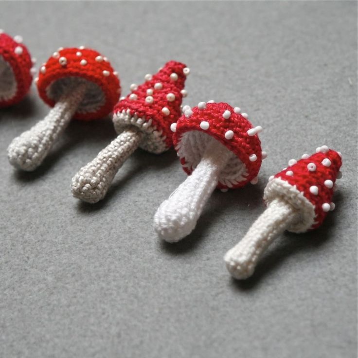 four small knitted mushrooms sitting on top of a gray table next to each other