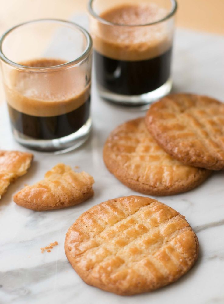 some cookies and two cups of coffee on a table