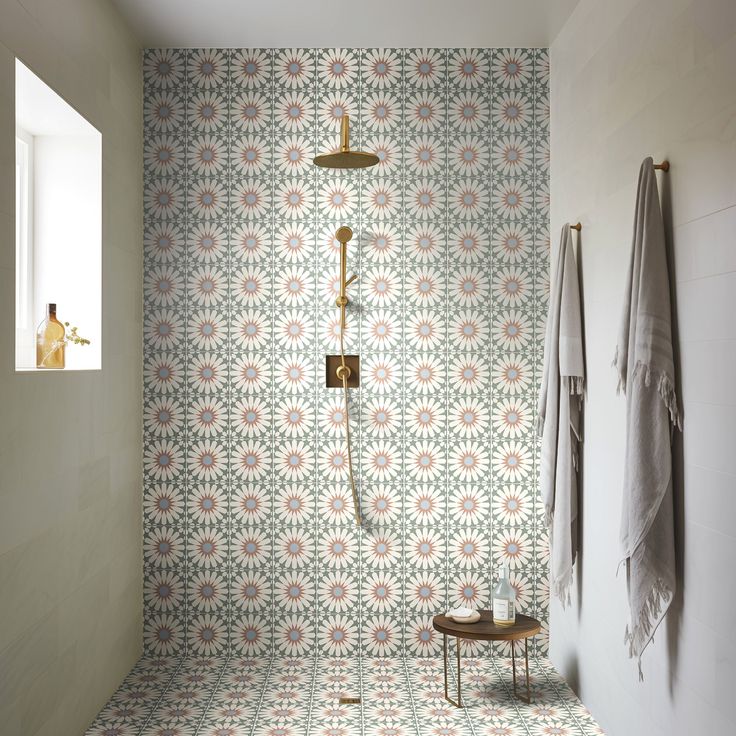 a bathroom with floral wallpaper and a shower head in the corner next to a bench