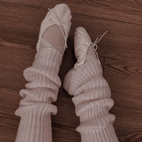 a pair of white ballet shoes on top of a wooden floor next to a string