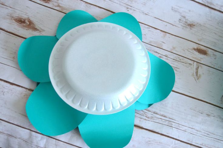 a paper plate sitting on top of a white wooden table next to a blue flower