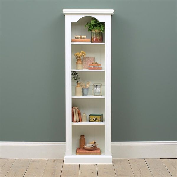 a tall white bookcase sitting on top of a hard wood floor next to a gray wall