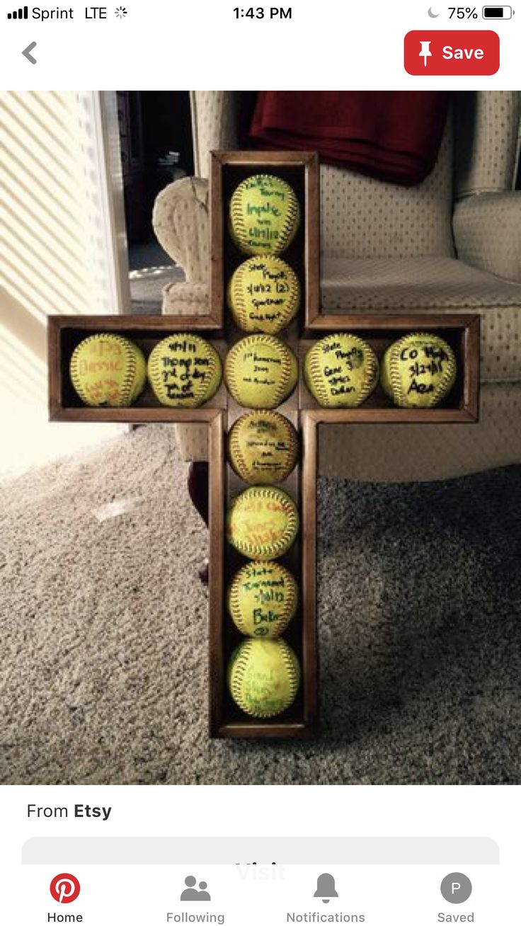 a wooden cross made out of baseballs on the floor in front of a couch