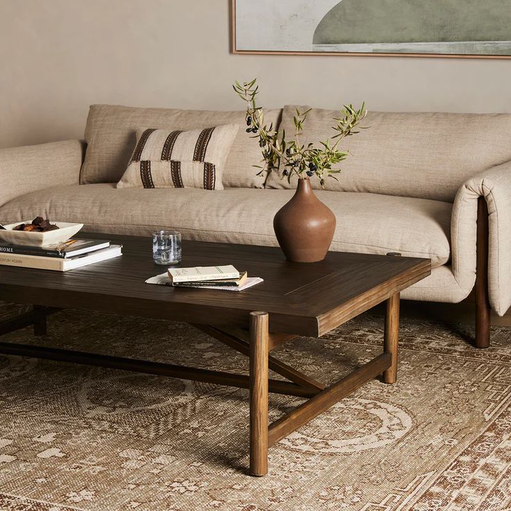 a living room with a couch, coffee table and vase on the floor in front of it