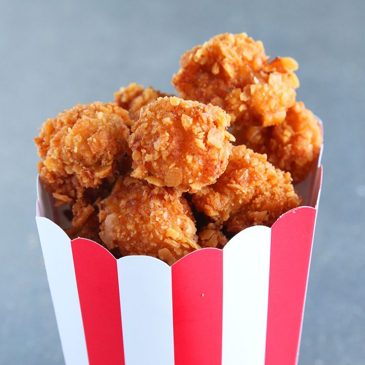 a paper basket filled with fried food sitting on top of a table next to a red and white striped cup