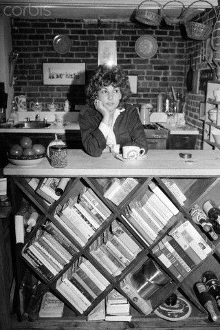 black and white photograph of a woman sitting at a counter with books on the shelves