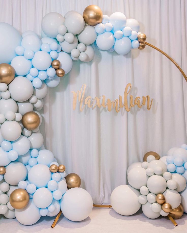 the balloon arch is decorated with gold, white and blue balloons