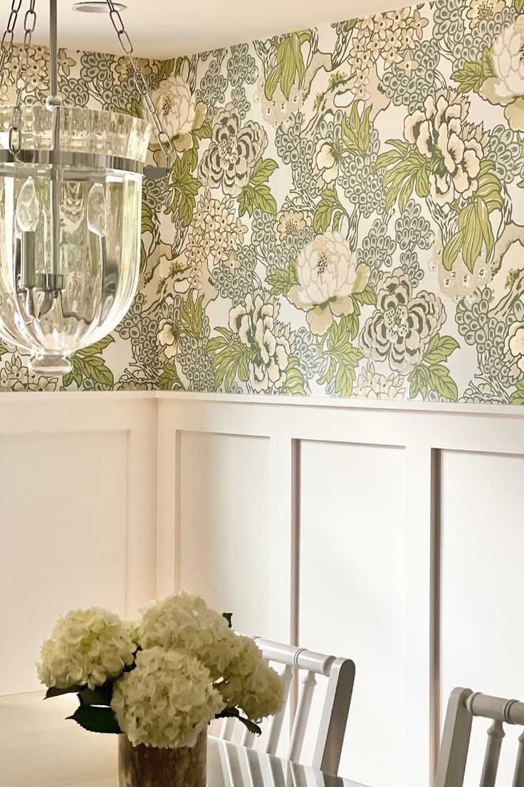 a dining room table and chairs with flowers in vases on the table next to it