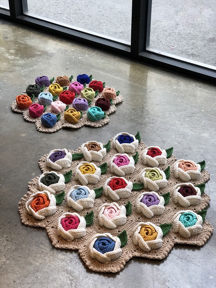 two crocheted rugs on the floor with flowers in them and one is made out of yarn