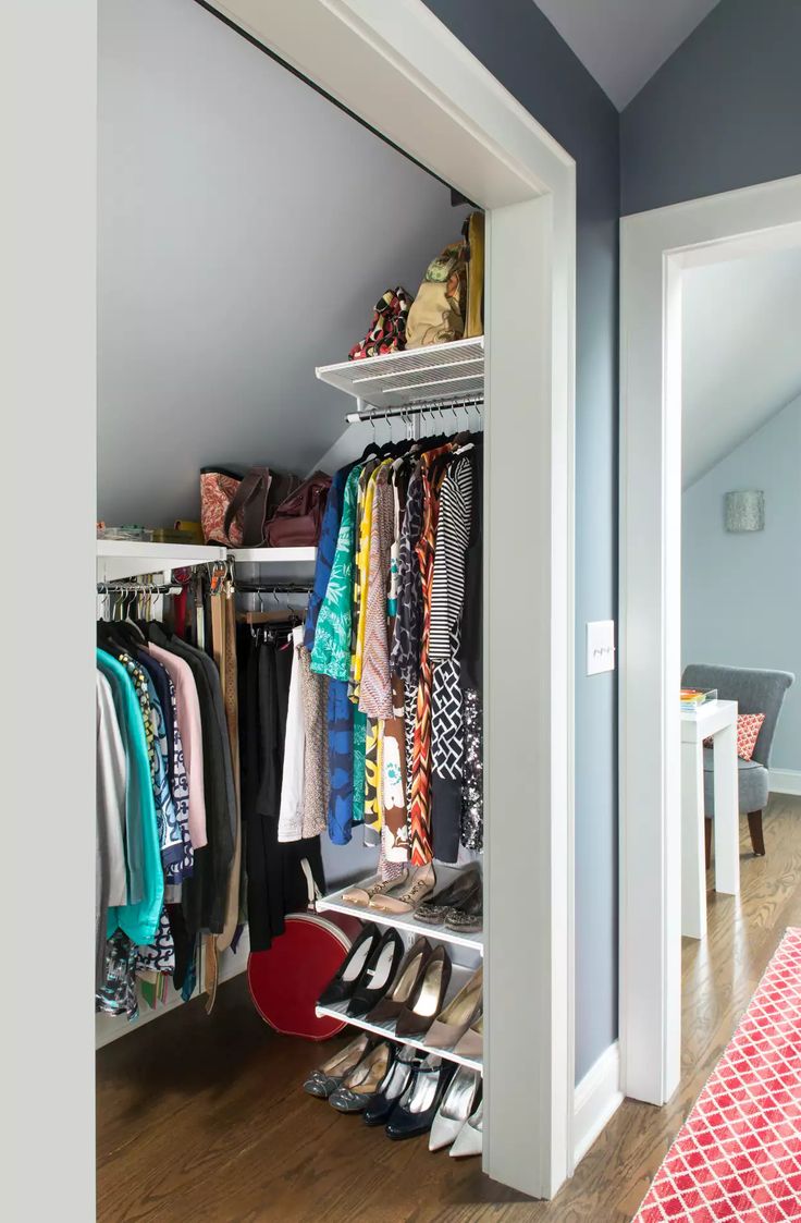 an open closet with clothes and shoes hanging on the shelves next to a red rug