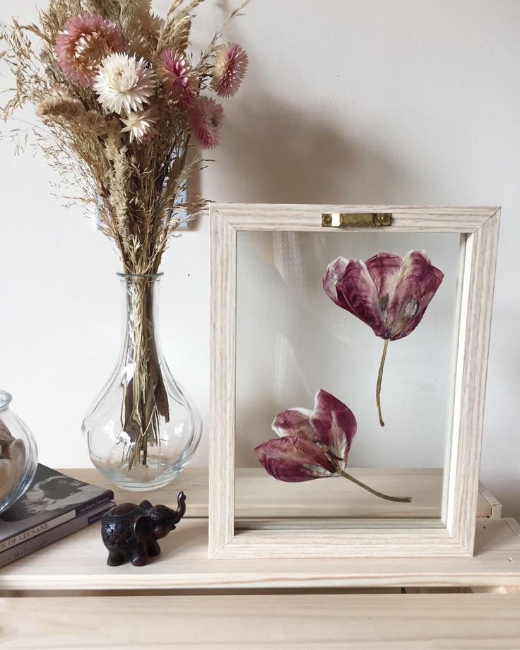 a vase filled with flowers sitting next to a glass frame