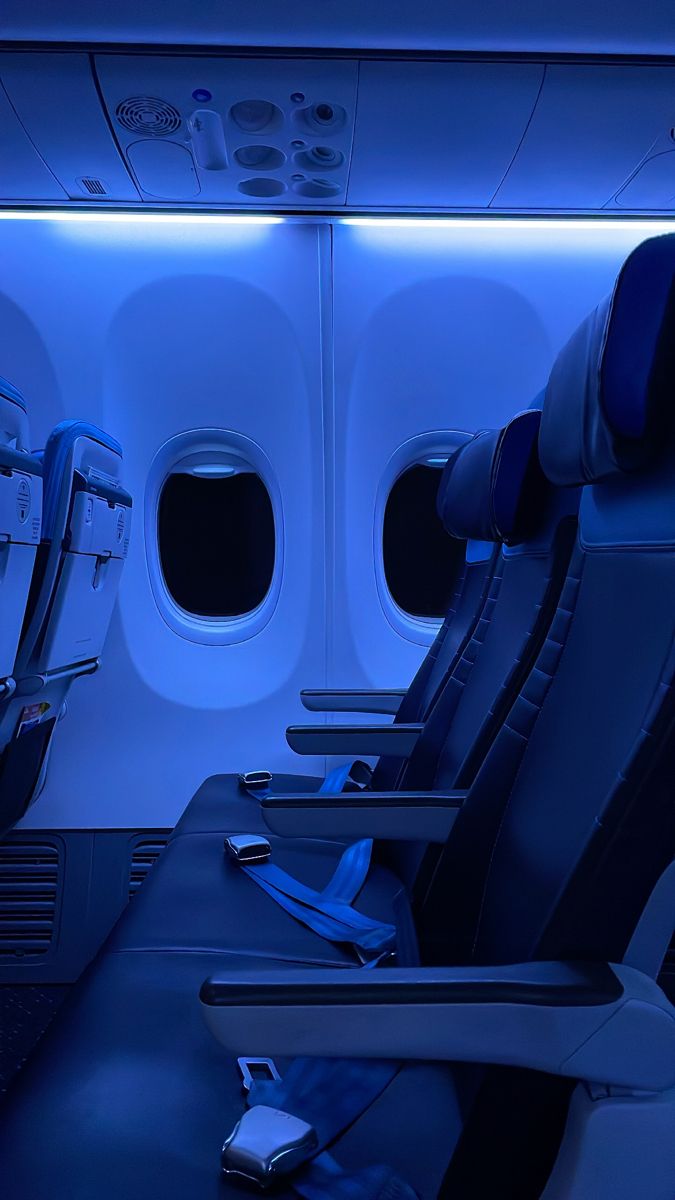 the inside of an airplane with blue lights and empty seats in front of them,