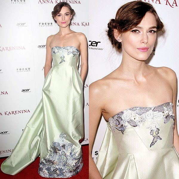 a woman in a strapless dress standing on a red carpet with her hands behind her back