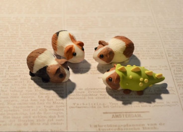 three small toy animals sitting on top of a piece of paper next to each other