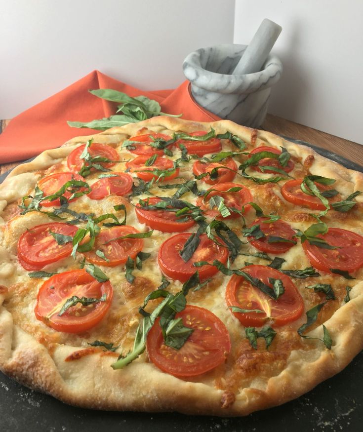 Sliced tomatoes and fresh basil on top of a cheese pizza.  A mortar/pestle, sprig of basil and an orange napkin in the background Canned Pizza Sauce With Fresh Tomatoes, Pizza Without Red Sauce, Pizza Without Tomato Sauce, Pizza With No Tomato Sauce, Pizza No Tomato Sauce, Pizza Recipes Without Tomato Sauce, Non Tomato Pizza Sauce, Pizza Sauce From Garden Tomatoes, Pizza Recipies