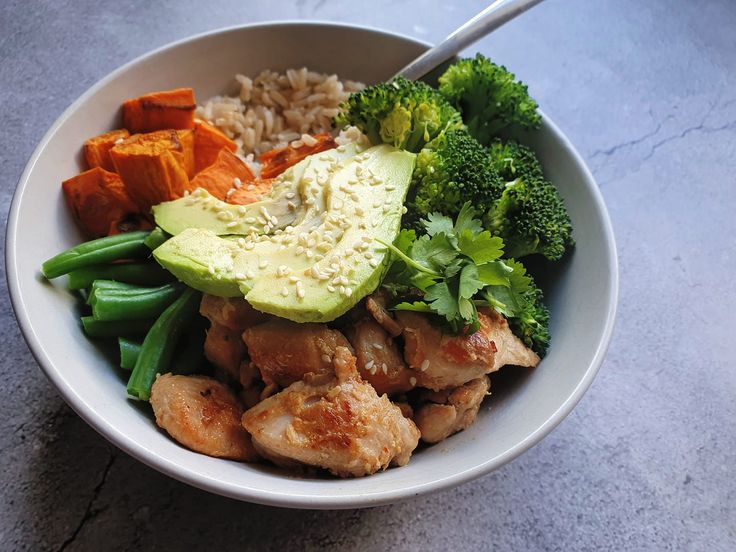 a white bowl filled with meat, vegetables and rice