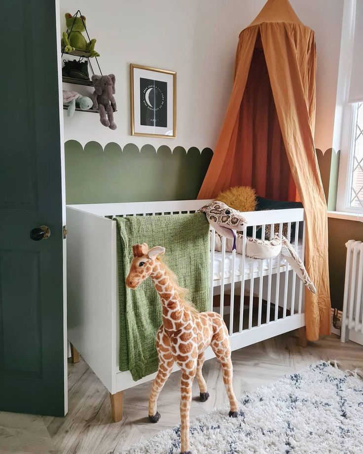 a baby giraffe standing next to a white crib in a room with green walls