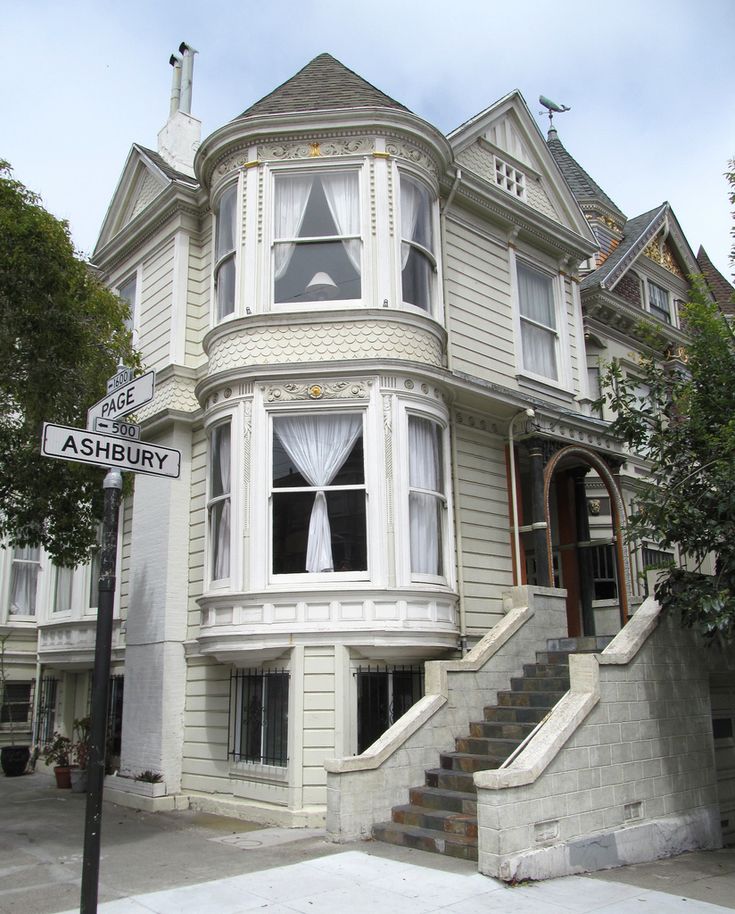 a large white house with stairs leading up to the front door and second story window