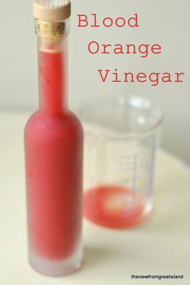 a red bottle sitting on top of a table next to a measuring cup with liquid in it