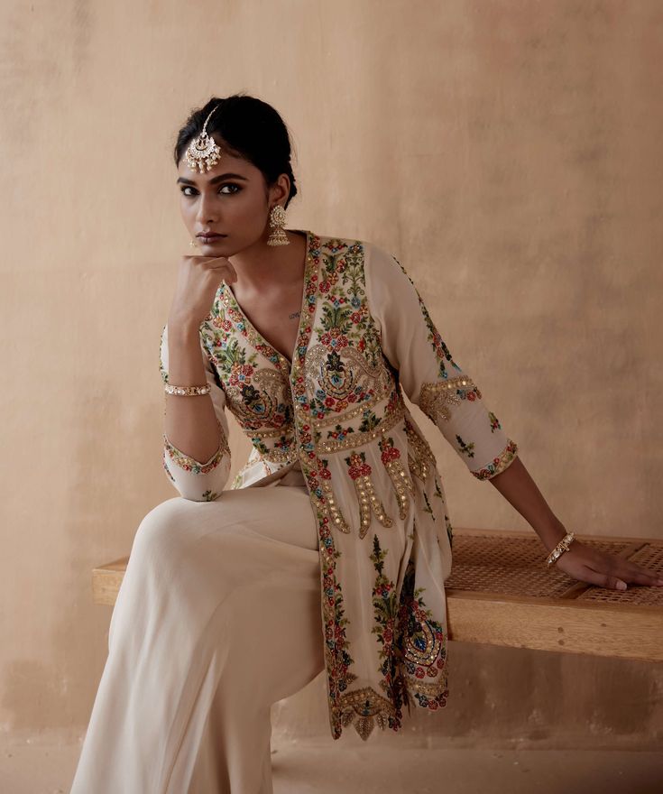 Editor's Note Presenting an elegant ivory kurta adorned with intricate floral thread embroidery, beautifully highlighted with various embellishments. This exquisite ensemble is paired with a stylish sharara, creating a sophisticated and graceful look perfect for special occasions or festive events. The combination of the detailed embroidery and the classic silhouette of the sharara adds a touch of timeless charm, making this outfit a tasteful choice for those who appreciate classic beauty with a Floral Thread Embroidery, Detailed Embroidery, Charm Making, Thread Embroidery, Thread Work, Classic Beauty, Classic Silhouette, Floral Embroidery, Diwali