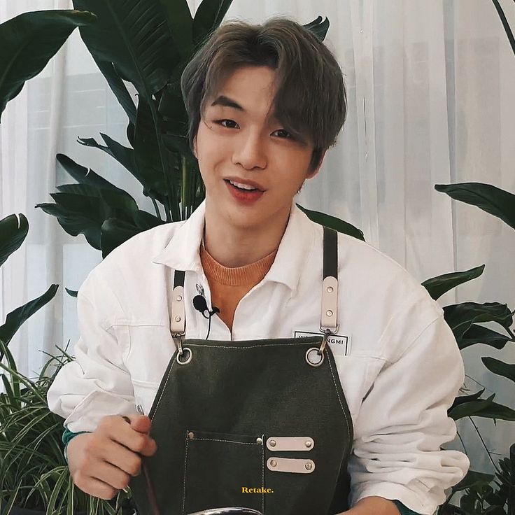 a man is holding an apron in front of a potted plant