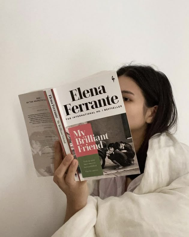 a woman is reading a book in bed