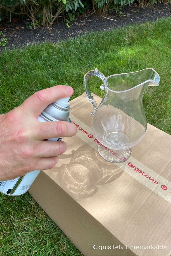 a hand is holding an empty glass pitcher on top of a cardboard box