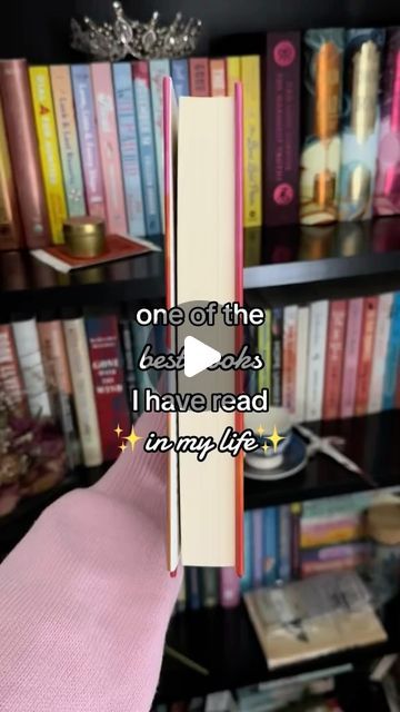 a book shelf filled with lots of books and a pink blanket on top of it