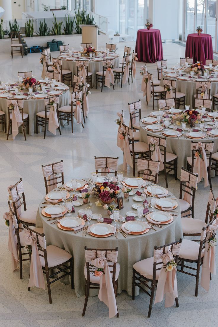 tables and chairs are set up in the middle of a room with pink linens on them