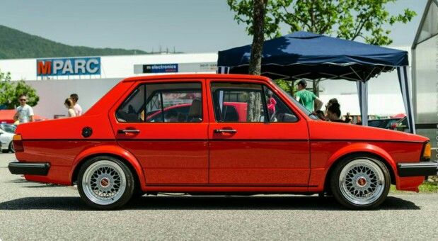 an old red car parked in front of a tent