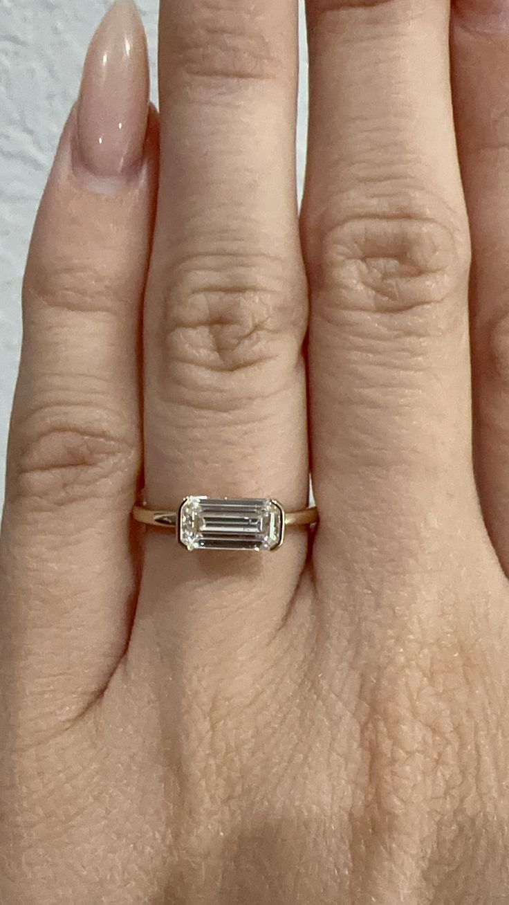 a woman's hand with a ring on it that has an emerald stone in the middle