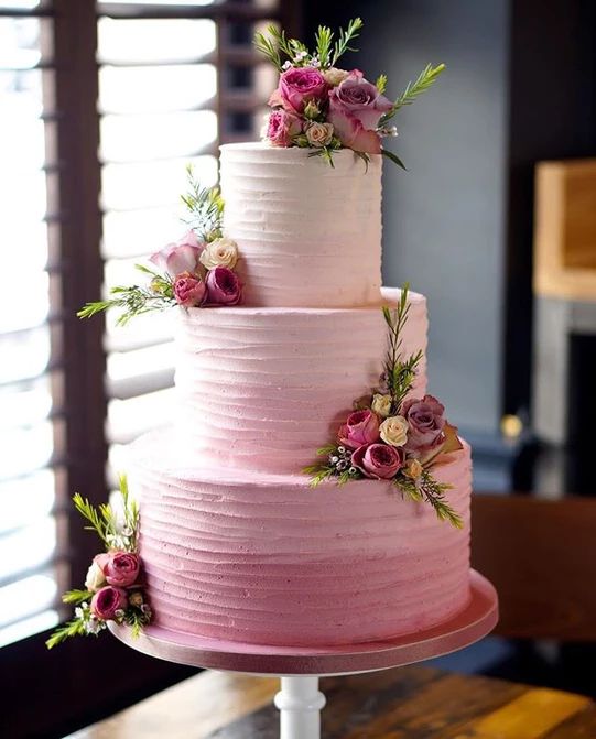 a pink wedding cake with flowers on the top and bottom is displayed in an instagram