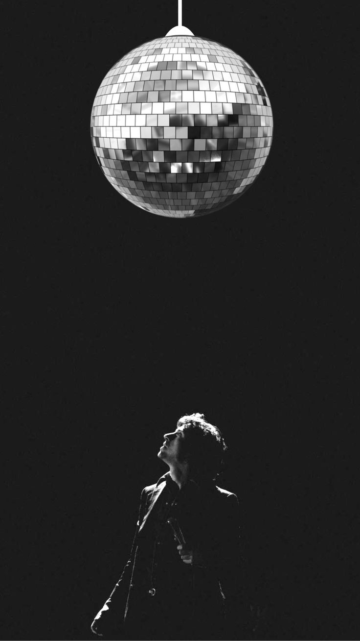 a person standing under a disco ball in the dark