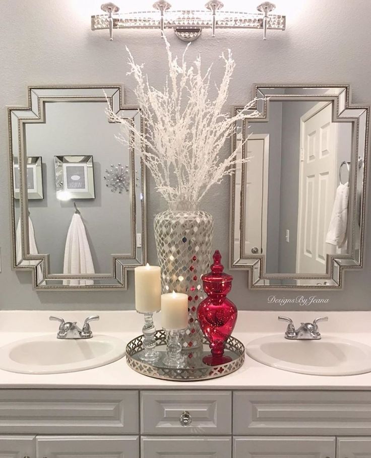 a bathroom with two sinks, mirrors and flowers in a vase on the counter top