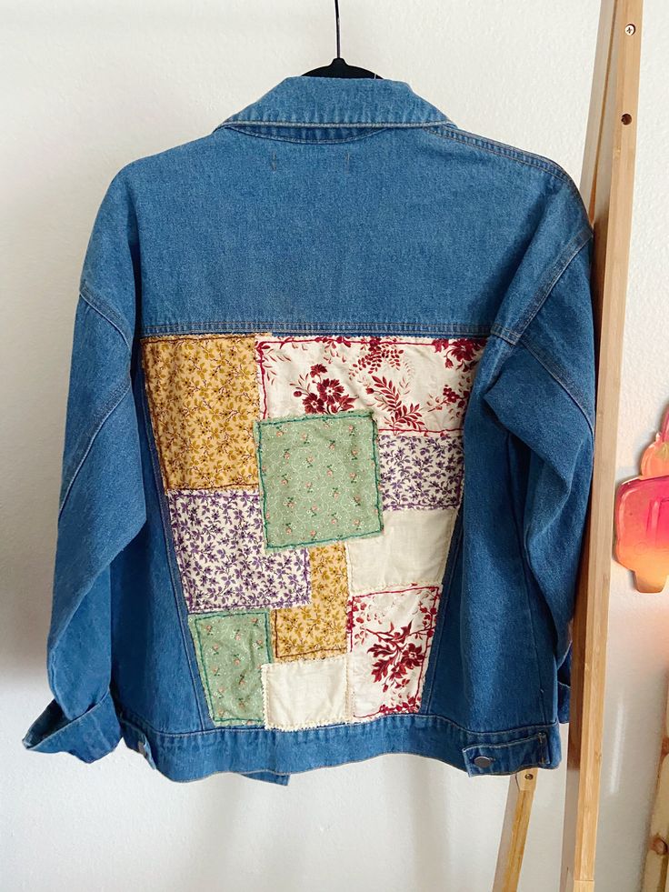 a blue jean jacket hanging up against a wall