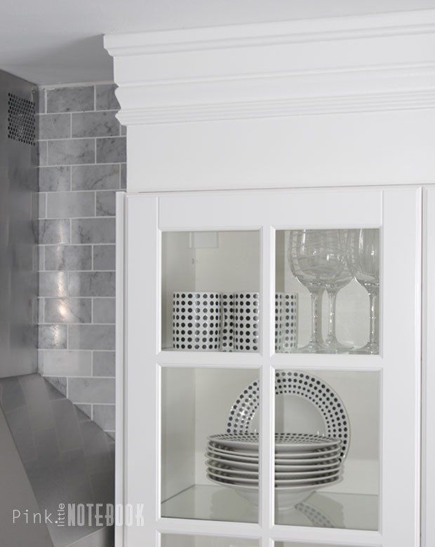 a white cabinet with glass doors and dishes in it