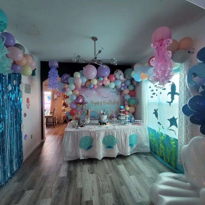 a room filled with balloons and decorations for a mermaid themed birthday or baby's first birthday