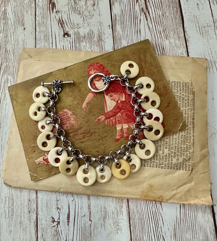 a close up of a bracelet on top of a piece of paper with buttons attached to it