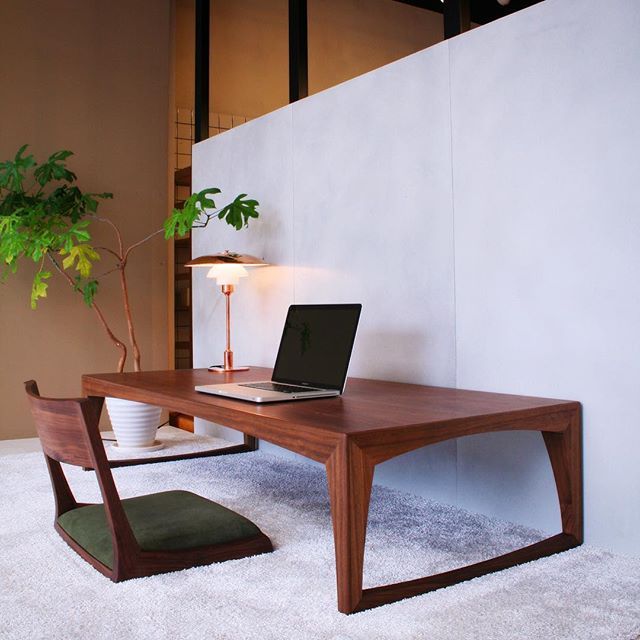 a laptop computer sitting on top of a wooden desk next to a potted plant