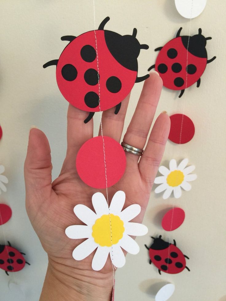 ladybugs and daisies are hanging from the ceiling with paper garlands on it