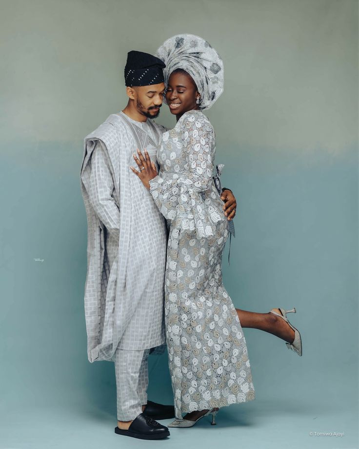 two people standing next to each other in front of a blue background wearing african clothing