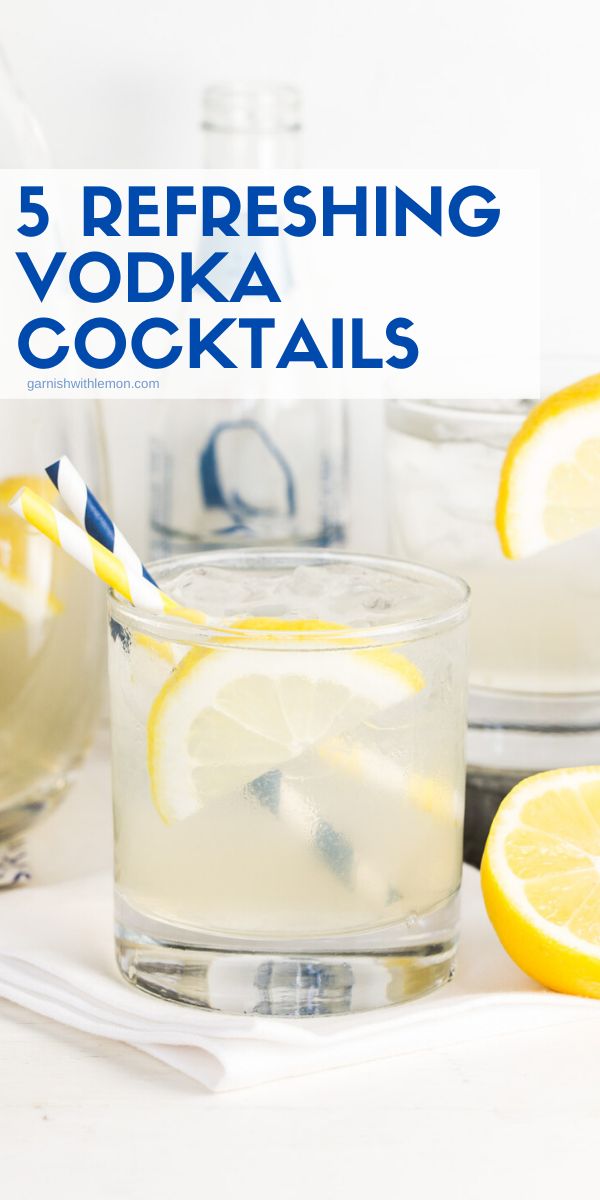 a glass filled with ice and lemons on top of a white table next to two glasses